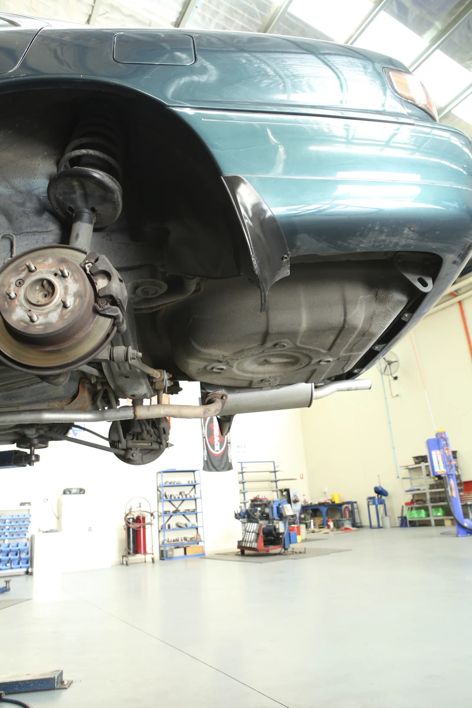 A raised vehicle with a wheel removed in the ATR workshop